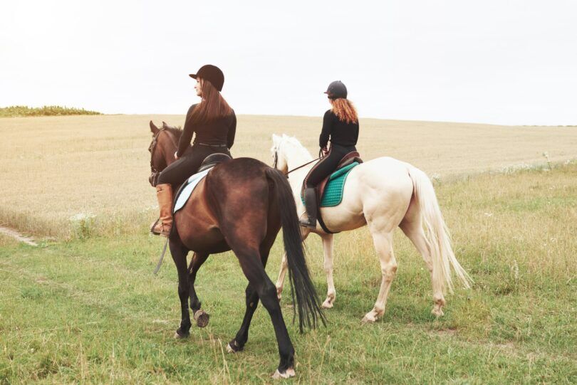 two women riding across a field