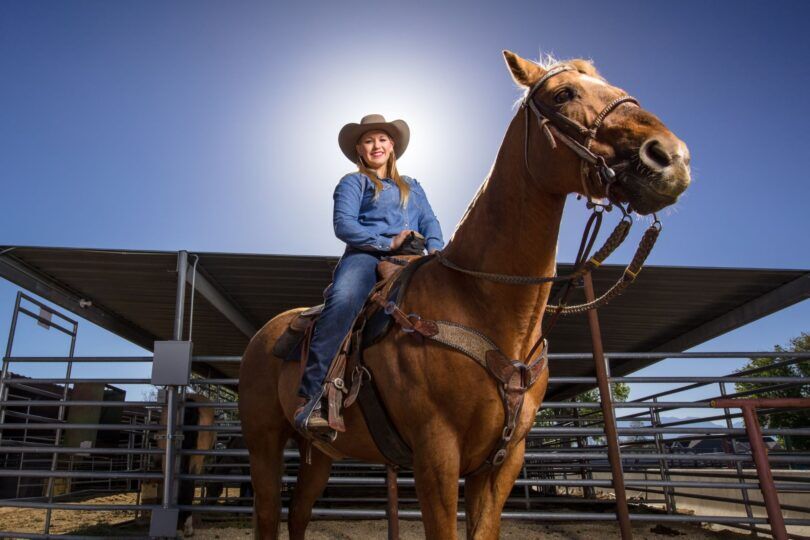 woman riding horse wearing a cowboy hat