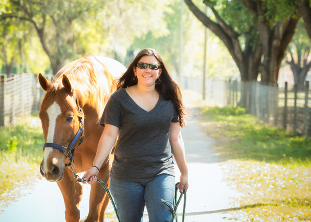 woman leading horse down road